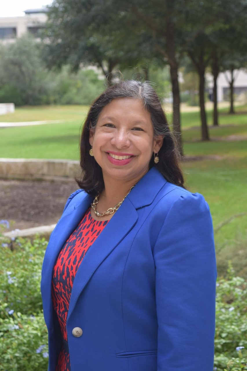 Guest Editor Mariela Rodriguez smiles, posing for a picture outdoors in front of trees and a grassy hill.